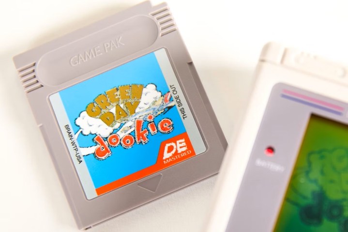 A gray Game Pak Game Boy cartridge with Green Day's dookie cover on it.