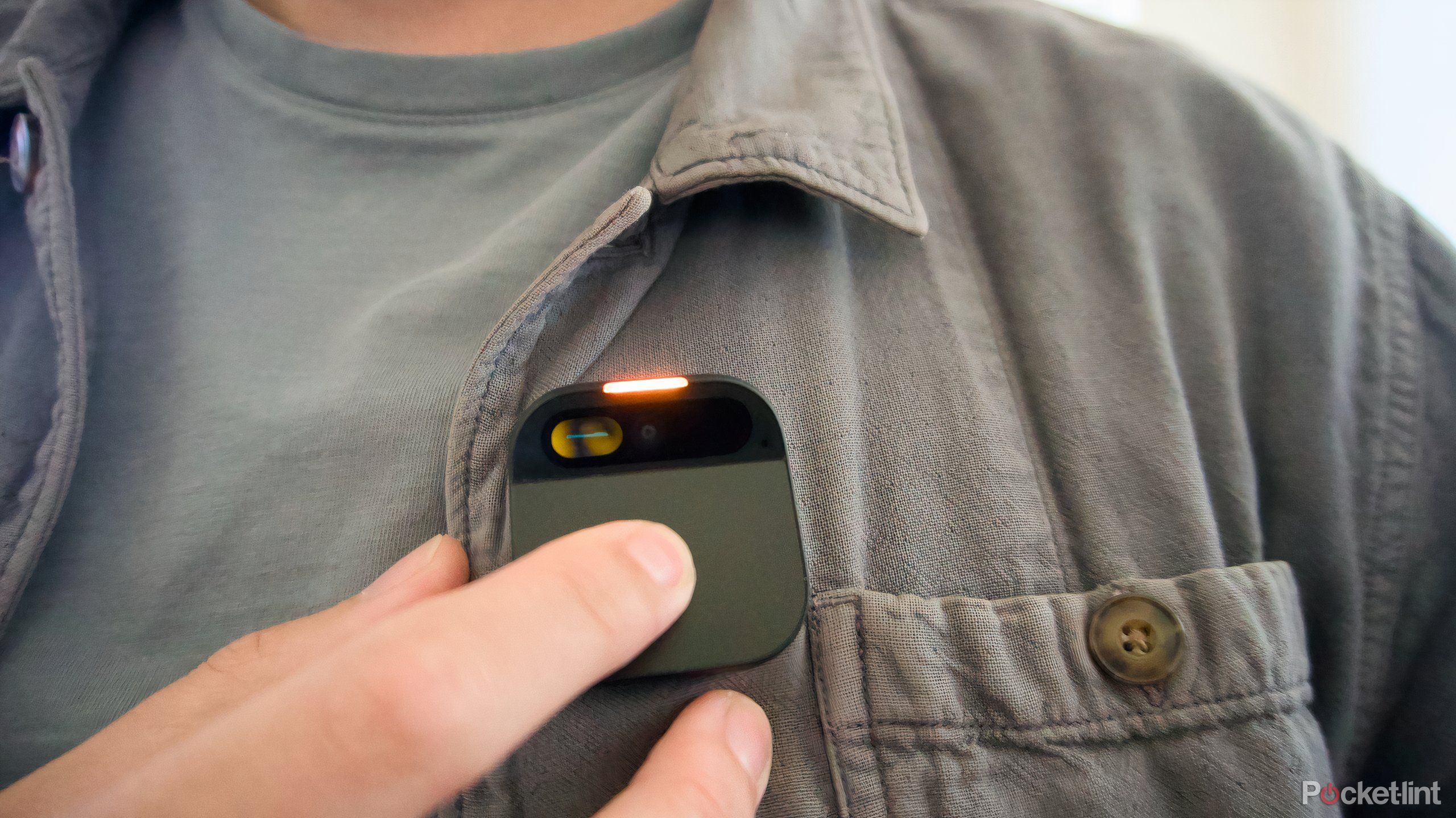 A finger pressing on the touch pad of the Humane AI Pin.