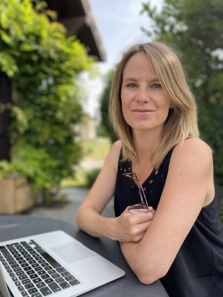 Nina Moerk, organisational consultant and meeting specialist based in Geneva, Switzerland, sitting in front of a computer in a garden.