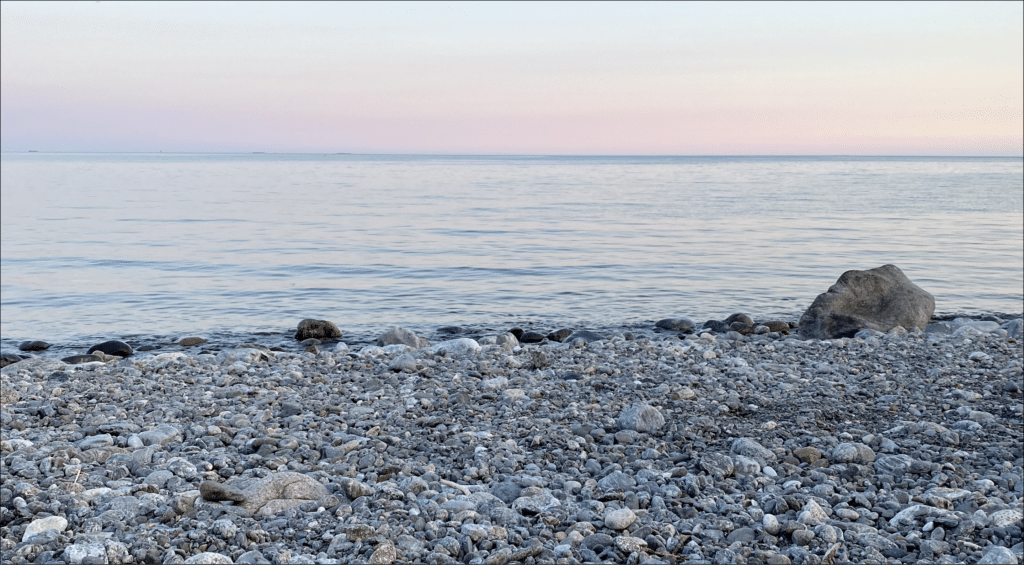 Sommarkväll med stenstrand och rosa solnedgång