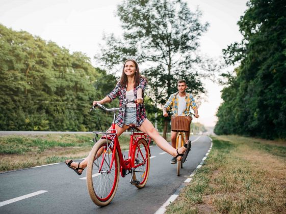 Young man and woman walking on retro bikes