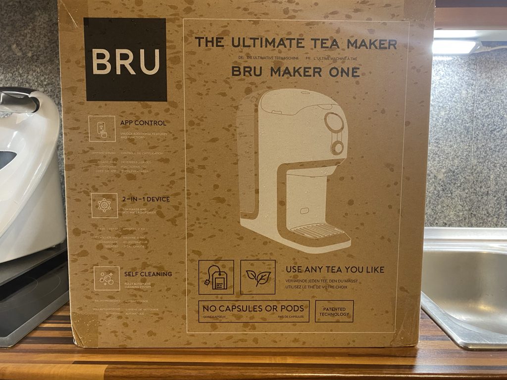 Der Umkarton der BRU Teemaschine. Es ist die Teemaschine abgebildet und links  oben das Logo von BRU. 