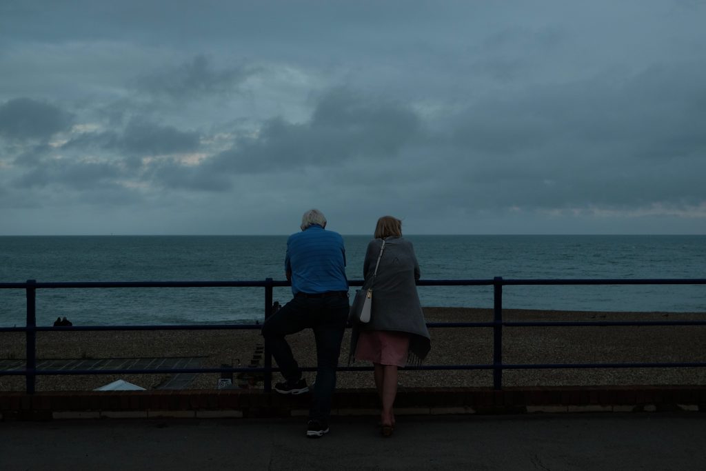 Par som står tæt sammen og kigger ud over havet i tusmørke