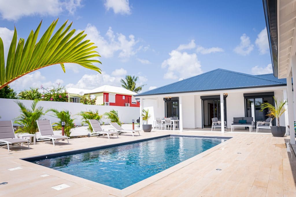 Piscine avec villa bleu et blanche en journée