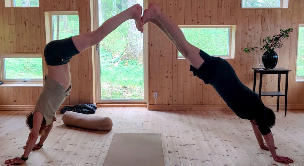 Två män som står på händer i en ljus yogasal