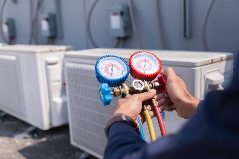 Technicien frigoriste utilisant un manifold pour vérifier la pression d’un système de réfrigération commerciale