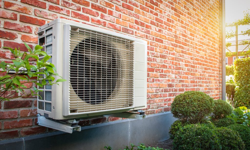 Unité extérieure de climatisation installée sur façade en briques rouges – système de clim pour maison ou commerce