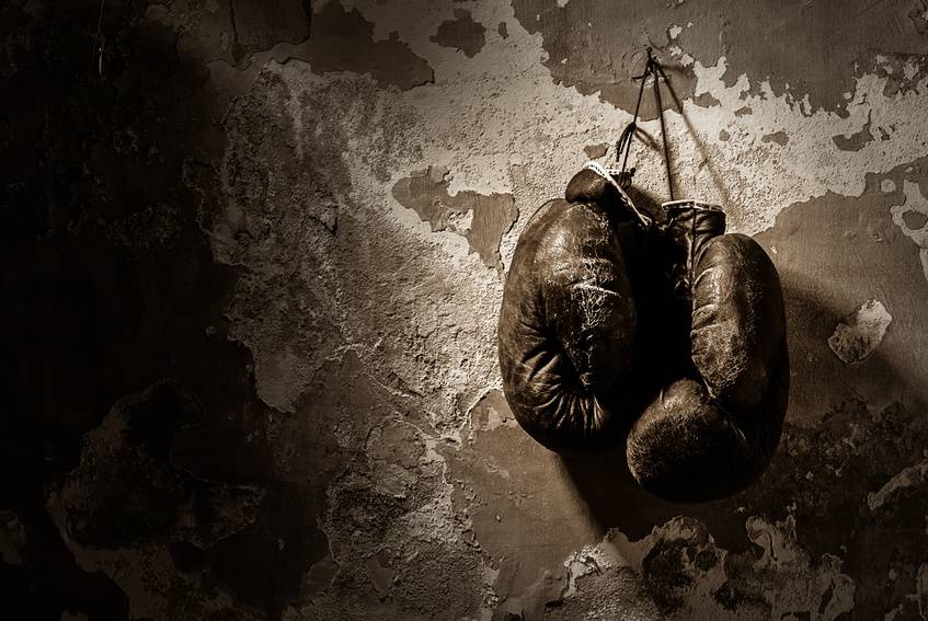 old boxing gloves hang on nail on texture wall