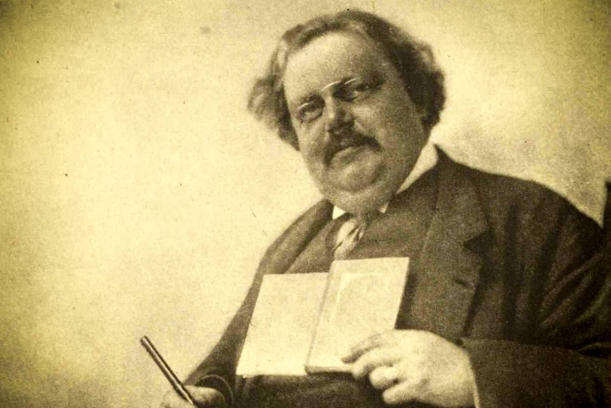 web-gk-chesterton-holding-book-pen-hector-murchison-public-domain-via-wikipedia