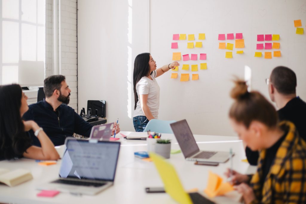 A person presenting at a whitewall to a team