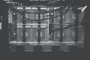 An image of some servers in black and white covered in wires. 