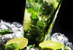 Fresh drink with ice, green mint and lime on black background