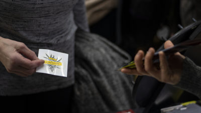 Kuvassa käsi, joka pitää YAD:n kannabis-tarraa.
