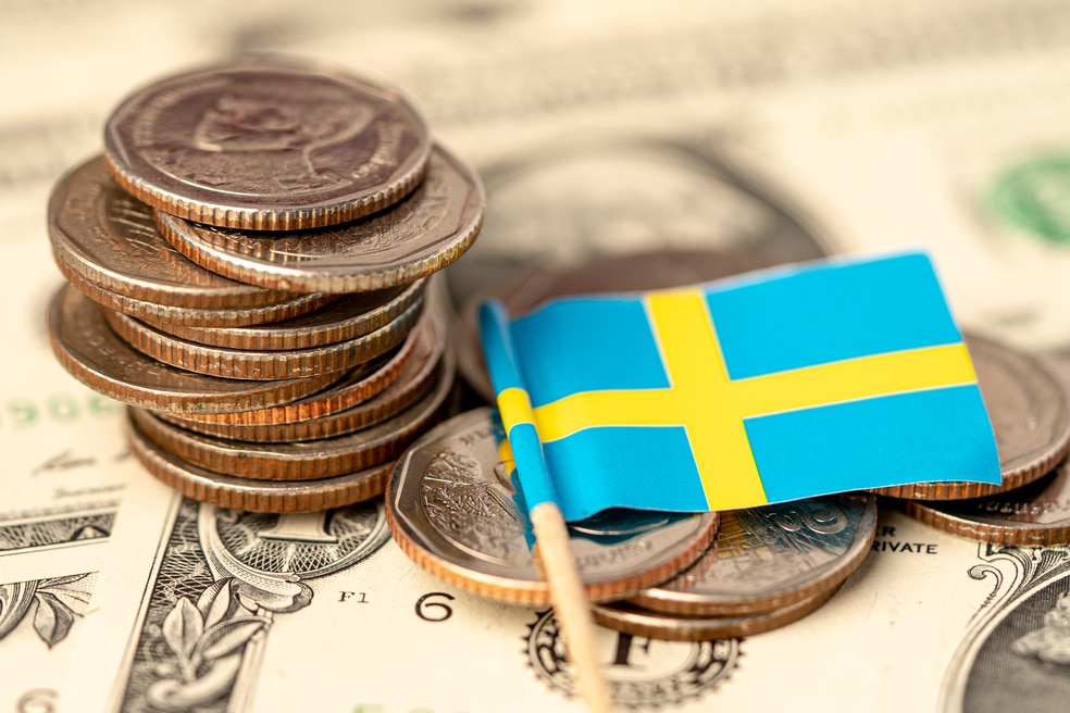 Stack of coins with Sweden flag on USA America dollar banknotes.